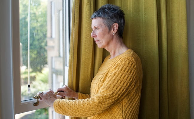 Older woman looking pensively out a window