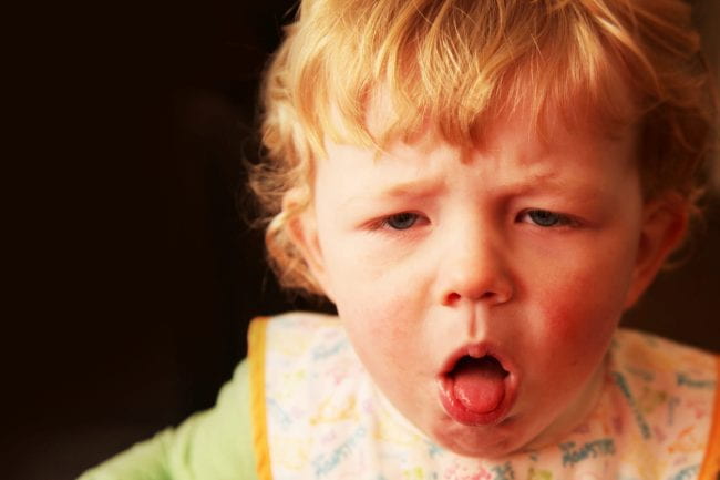 A young boy (18 months) with a nasty cough, coughing with his mouth open and tongue poking out